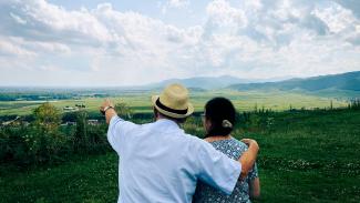 A man and a woman standing on top of a lush green field by Jametlene Reskp courtesy of Unsplash.